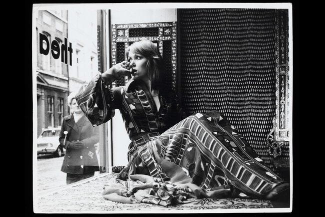 Модель, сидящая у окна магазина Thea Porter. На ней: платье из шелк-шифона с ковровым принтом Samawa, созданным Сандрой Манро. Грик-стрит, Соха, около 1970